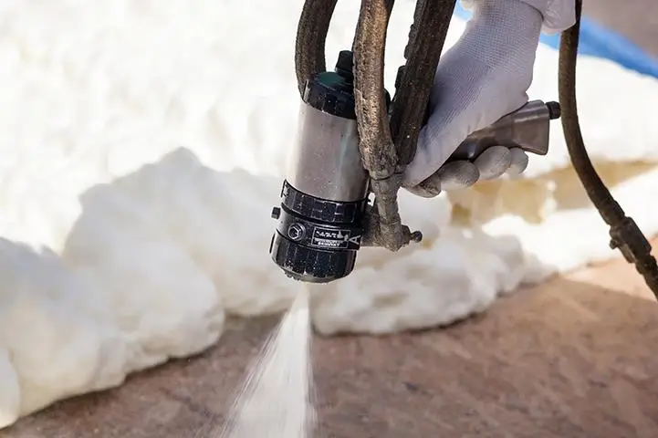 closeup of hand holding foam insulation sprayer spraying foam 1 4 5 1